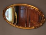 Miroir ovale, vers 1925, en bois stuqué doré, à décor...