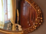 Miroir ovale, vers 1925, en bois stuqué doré, à décor...