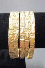 Cinq bracelets joncs en or bas-titre ciselé (poinçons E.T.). Poids...